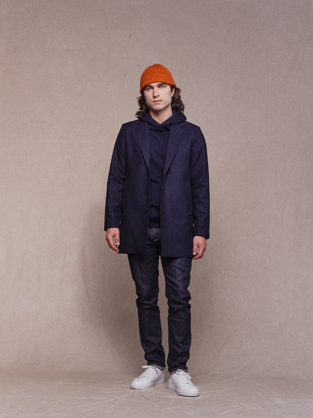 Full model shot of Asuwere Woollen Topcoat in Navy with navy hoodie and orange beanie