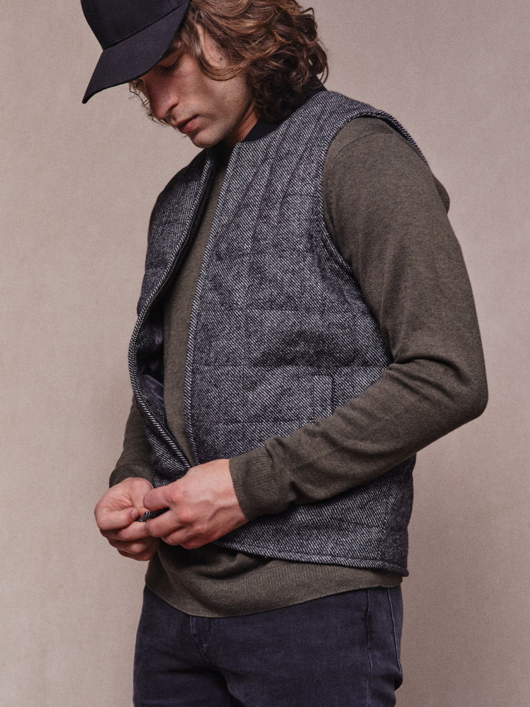 Model wearing Khaki Crew and zipping up Quilted Vest in Charcoal