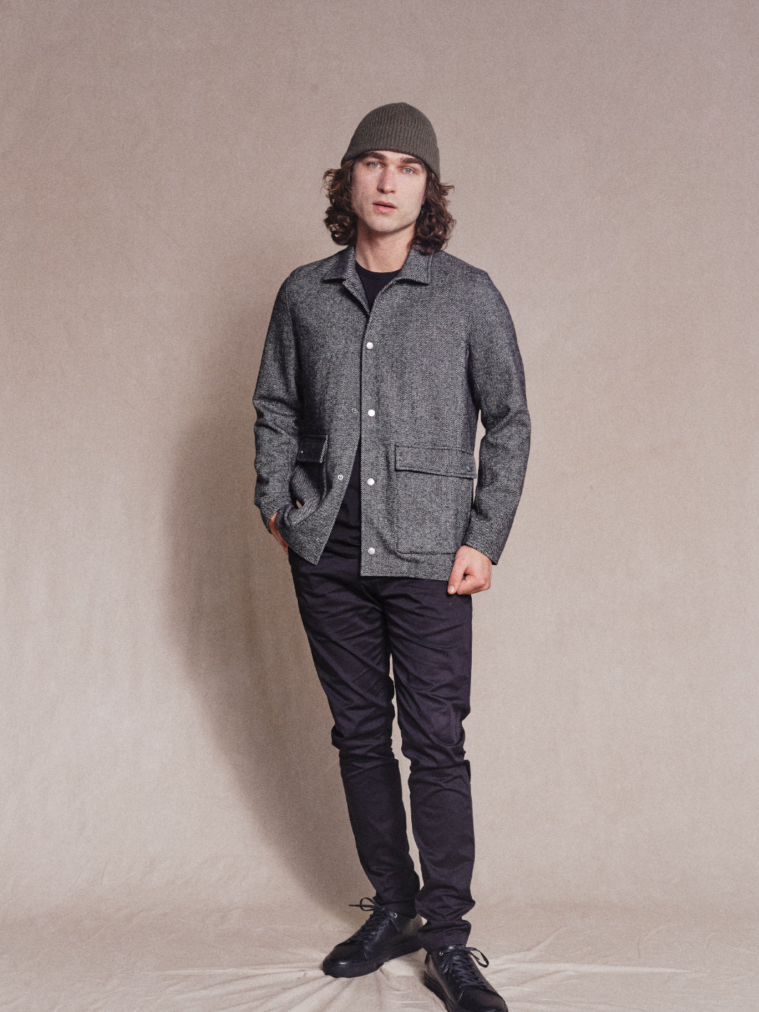Full length image of model wearing Heavy Woollen Overshirt in Charcoal with Khaki Beanie, Black Tee, Black Chinos and Black Sneakers