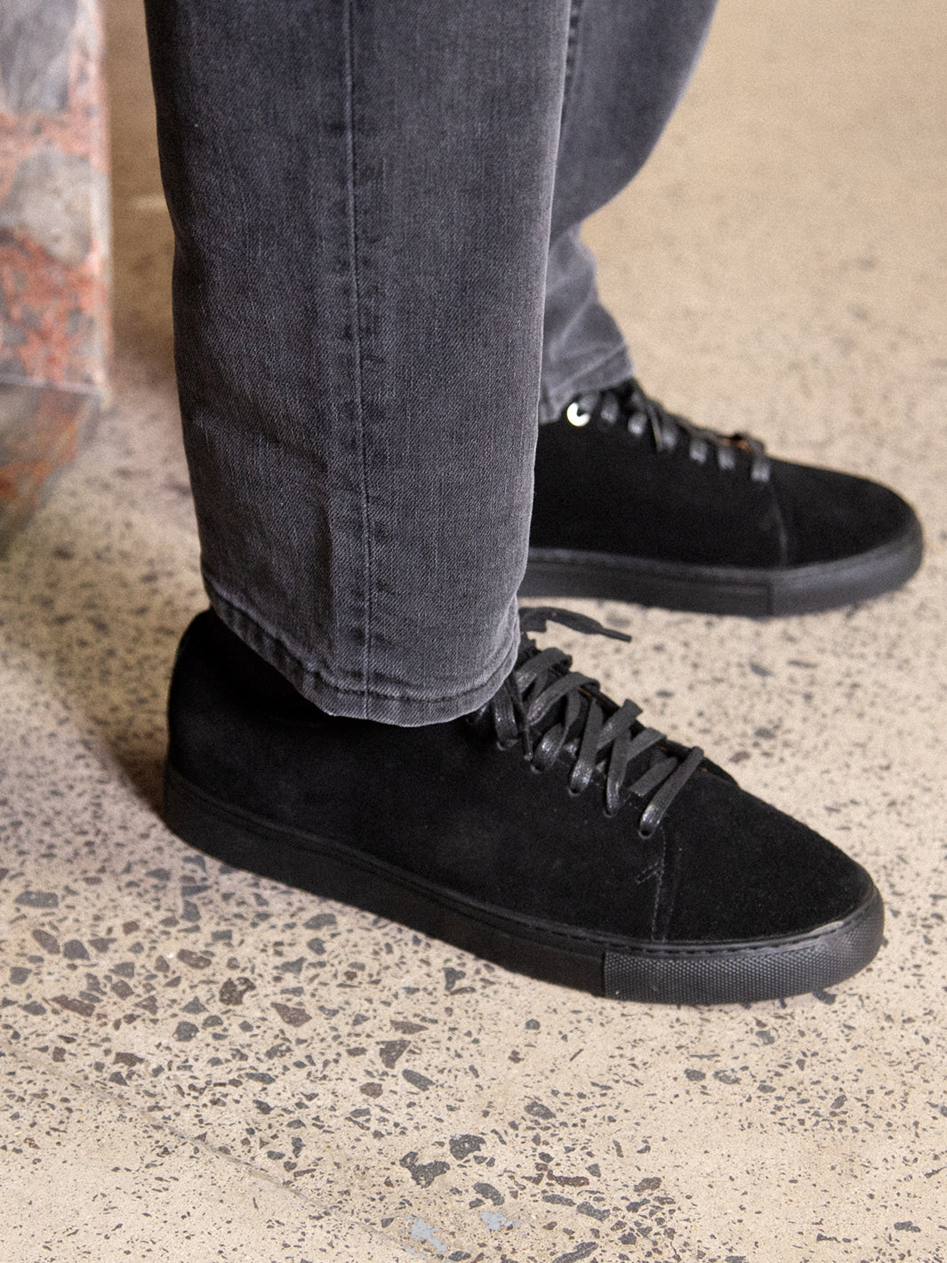 Close up detail shot of Asuwere black leather sneakers with washed black jean