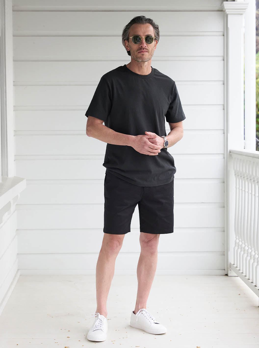 Model standing on white deck wearing Recycled Cotton Tee in Aged Black